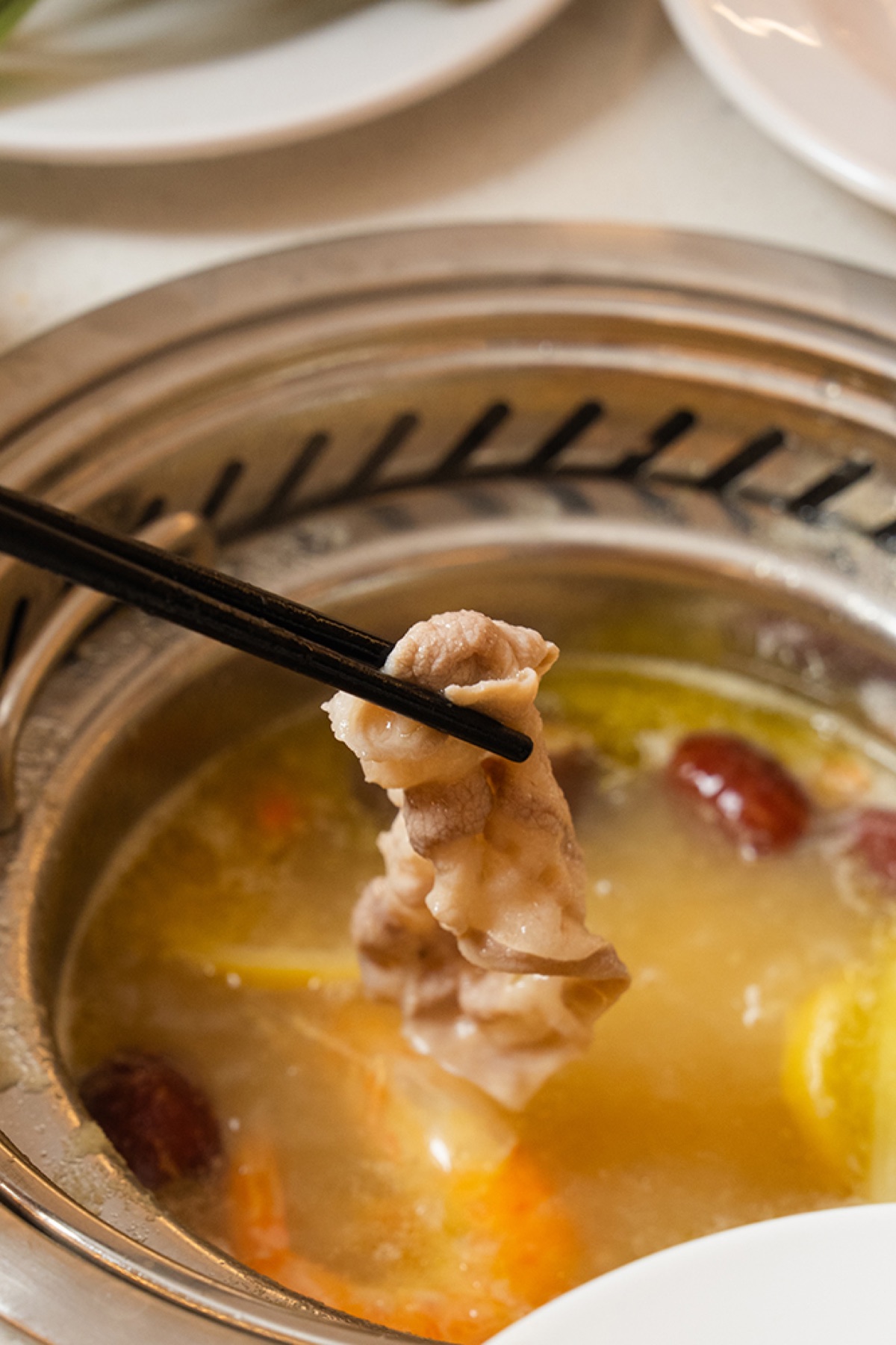 Sliced meat being cooked in an individual hot pot