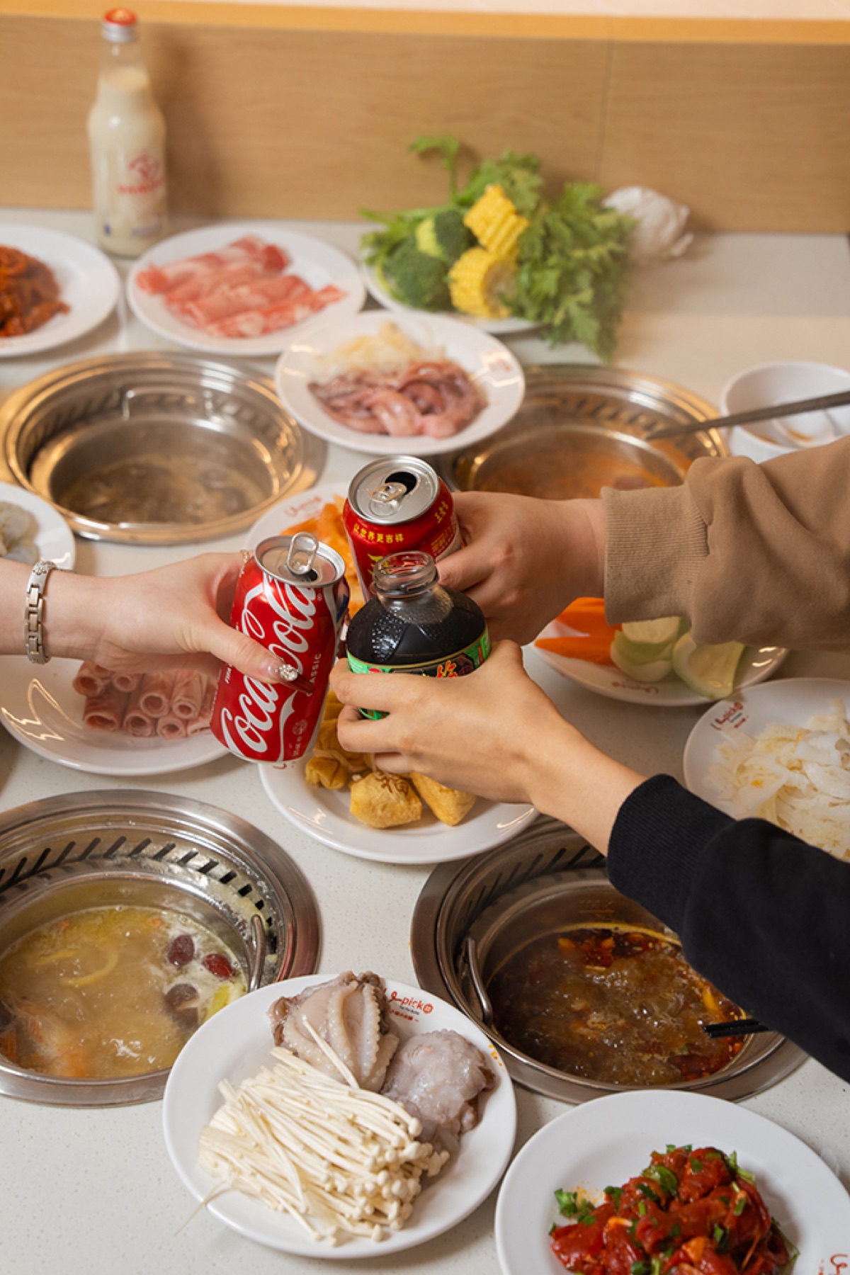 Friends raising drinks over a hotpot meal